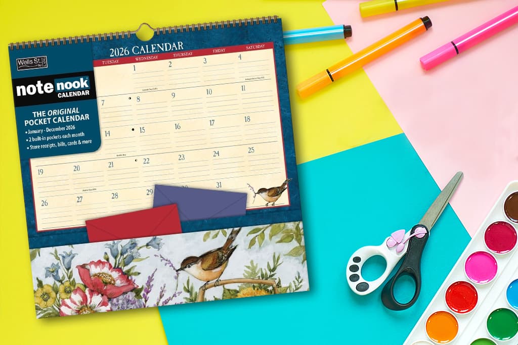 A 2026 Note Nook pocket calendar surrounded by colorful craft supplies, scissors, and markers on a bright desk setup