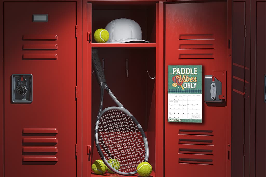 Mini wall calendar hanging inside a red sports locker with tennis balls, racket, and white cap