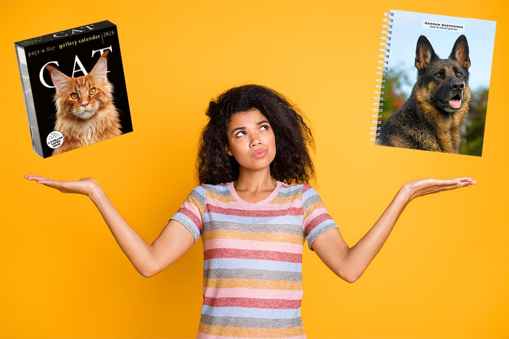 Woman weighing the choice between a cat-themed desk calendar and a German Shepherd spiral planner, symbolizing calendar and planner organization