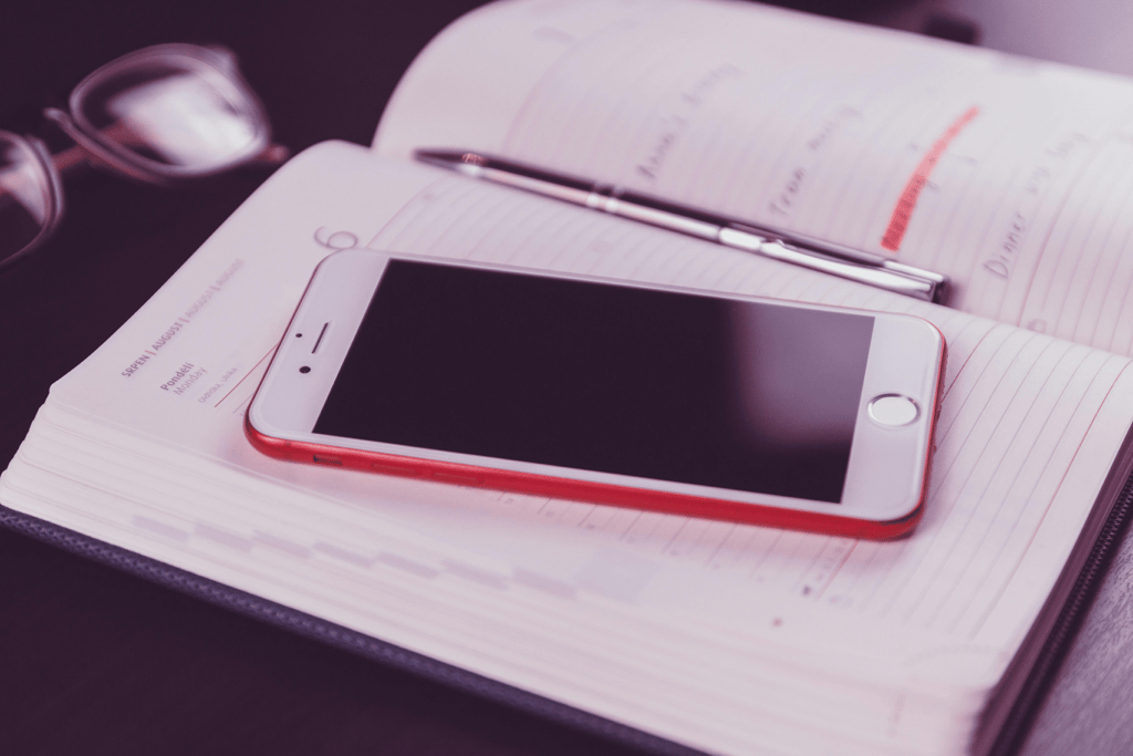 Planning on a monthly calendar with phone and desk essentials nearby